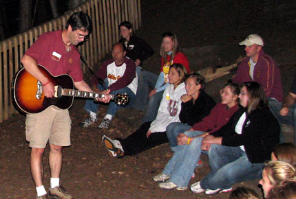 Andre Nault plays the guitar outdoors at night for a group of people