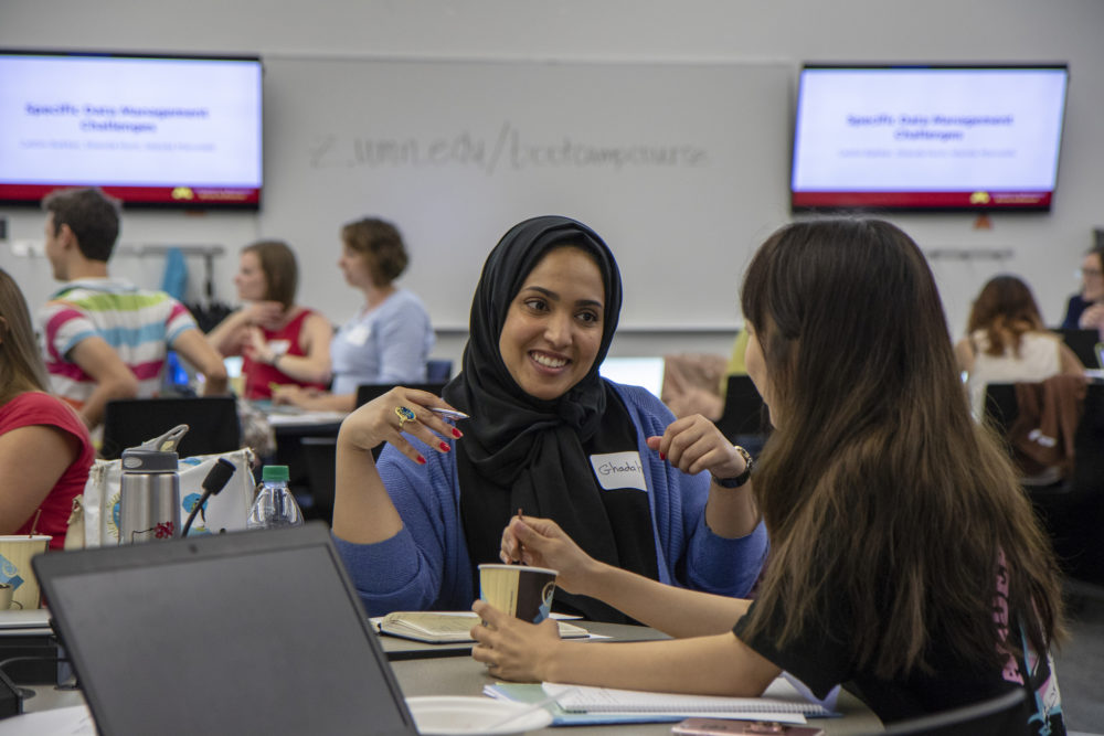Two graduate students at Data Management Boot Camp chat and laugh with each other during a break between sessions.