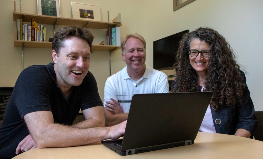 Steve Manson, Shane Nackerud, and Kristi Jensen looking over their work on a laptop computer