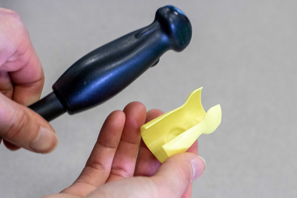Ultrasound probe being held next to a probe cover, showing the back of each to show how it snaps on