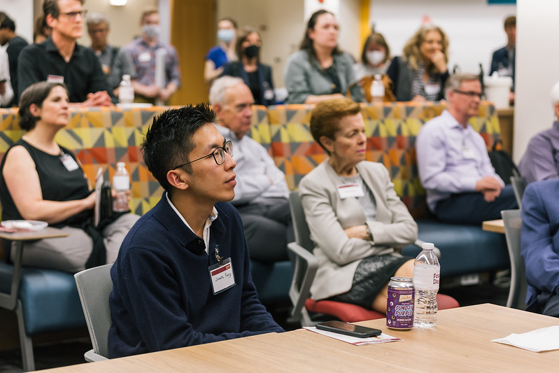 an audience of dozens pays rapt attention to a student presentation