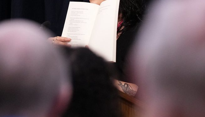 52795481927_8d37a1b139_c Sun Yung Shin holding up her book at the Pankake Poetry reading, 2023. Photo by Luke Logan