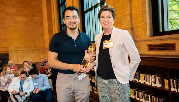 Student holding glass award next to professor at Founders Day 2023