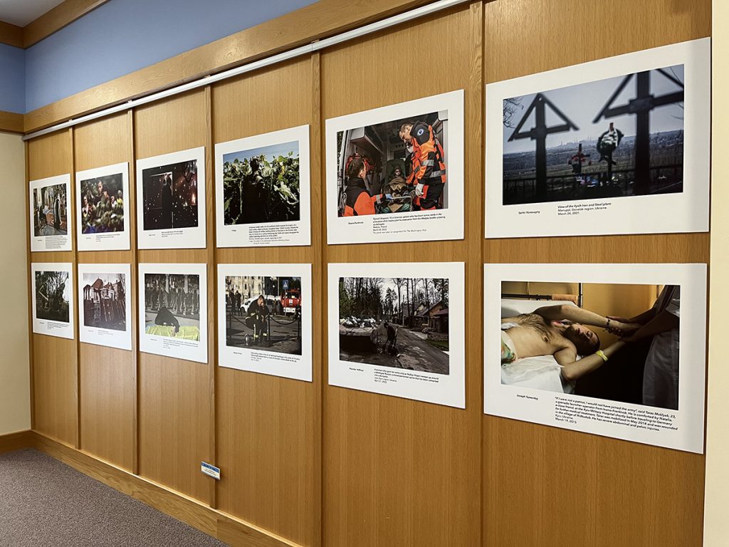 Wood paneled wall in Elmer L. Andersen Library with poster-sized photos on display from the exhibit Ukraine: War and Resistance