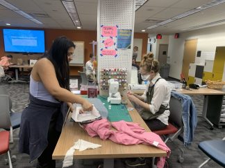 Annie Henly and a student mend items in the Breakerspace's sewing station.
