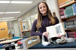 Bridget McKenna in the Wangensteen Library, holding a book on historic infant feeding.