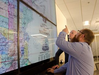 Ryan Mattke, Map & Geospatial Information Librarian, points out details on an 1871 map of Minnesota to Benjamin Wiggins, Program Director of the Digital Arts, Sciences, & Humanities (DASH) program.