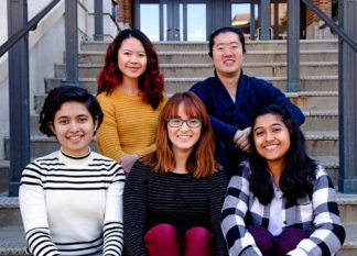 Five U of M Peer Research Consultants sitting on the steps outside of a library building