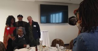 Four people having their photo taken at a celebration for Archie Givens, Jr.