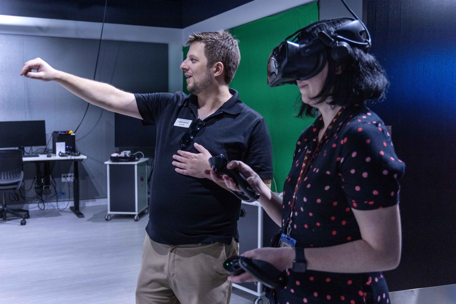 Library staff member shows someone how to use a virtual reality simulation in the VR Studio.