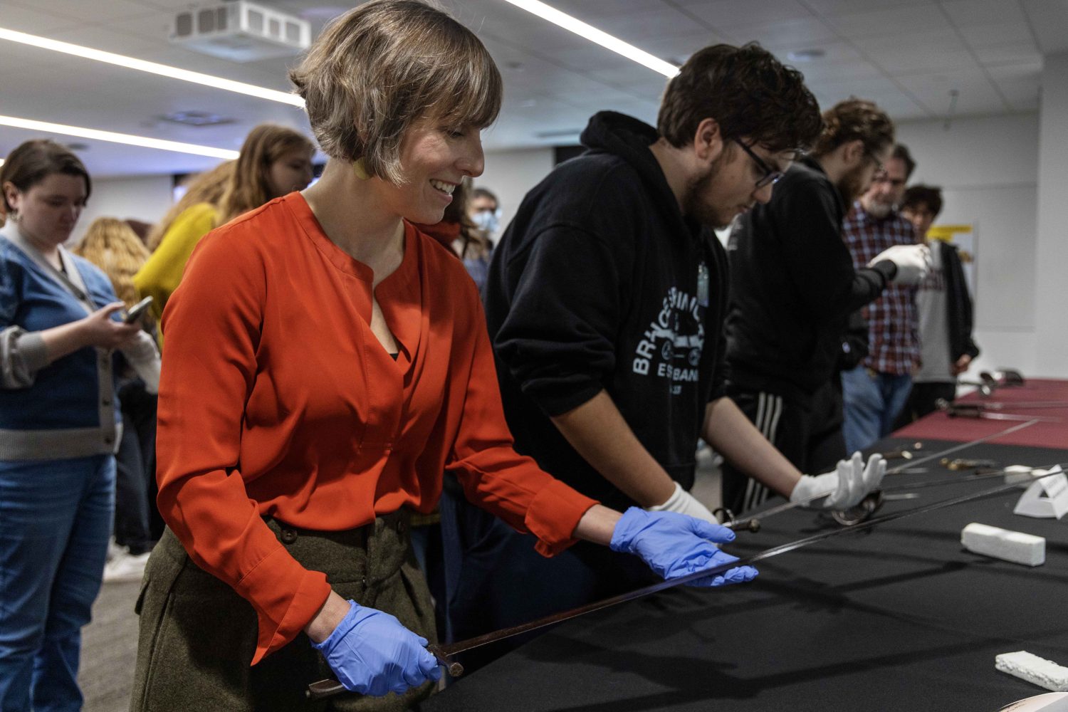 Erinn Aspinall, director of the Health Sciences Libraries, lifts an antique sword at the Wangensteen pop-up exhibit.