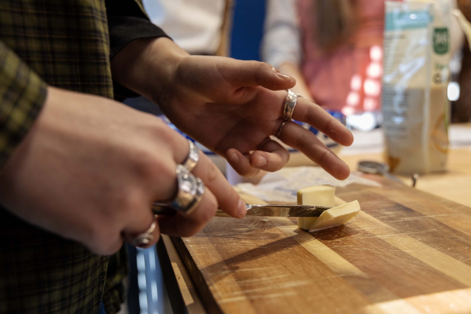 Close-up view of student's hands using a butter knife to cut a small pat of butter in half.