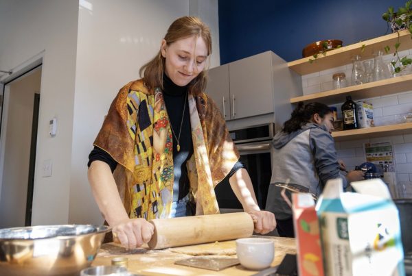 A student uses a rolling pin to roll out the beignet dough