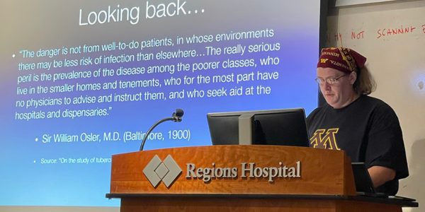 Person at podium in front of a projection screen.