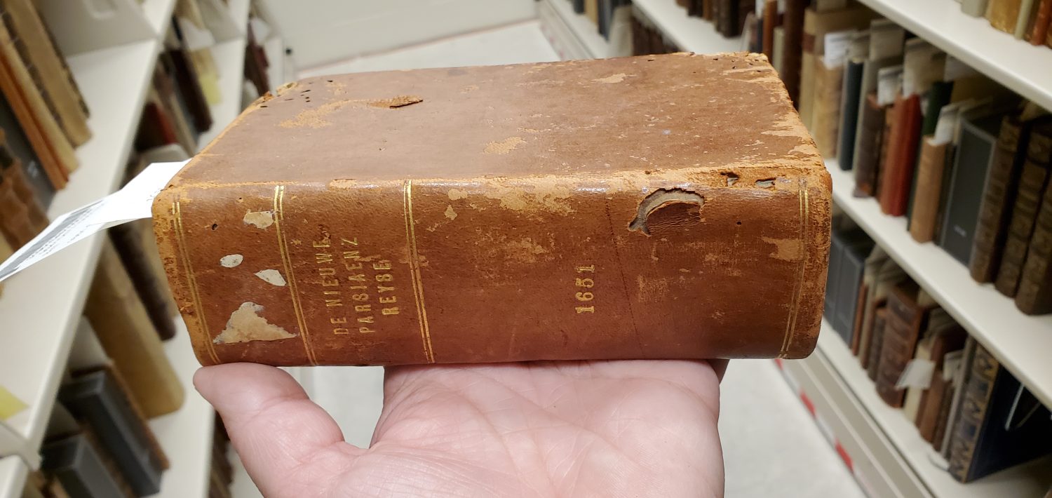 Small, brown book resting on a hand.