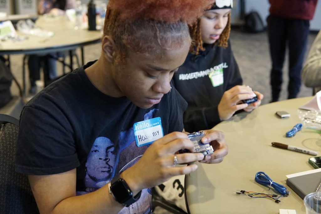 Two students connecting a breadboard to a microcontroller.