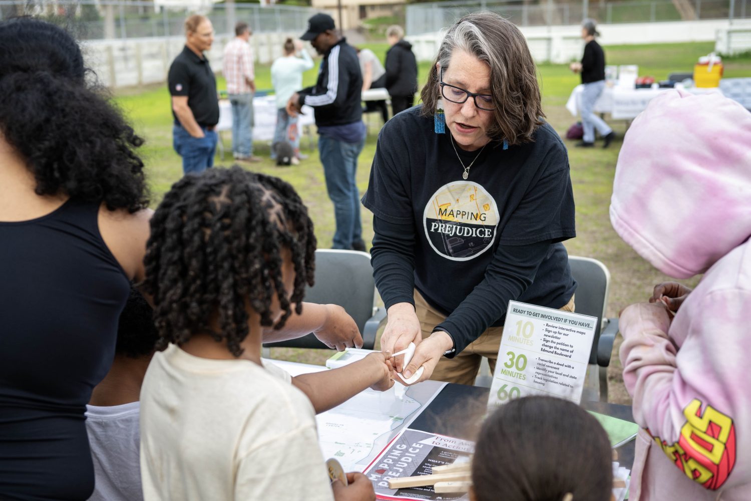Rebecca Gillette, the Mapping Prejudice community engagement lead, passes out stickers to neighborhood kids in Robbinsdale, Minnesota, on Friday, May 3, 2024. (Photo/Adria Carpenter)