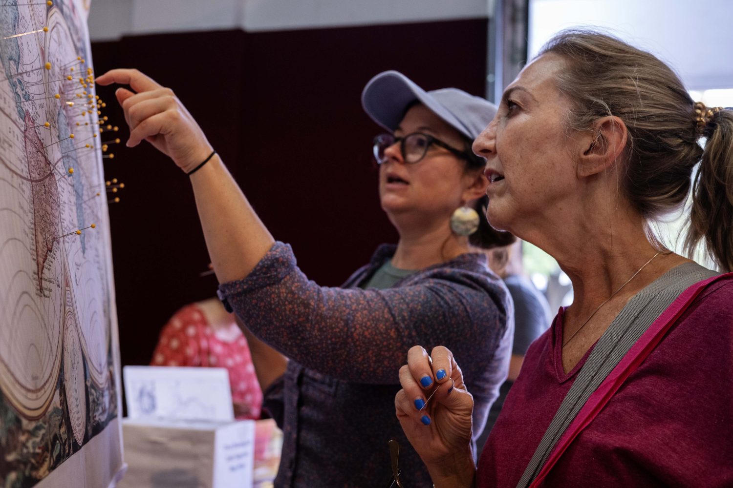 An attendee places a pin on the map to mark where she thinks her ancestors originated from, at the Center for Premodern Studies' booth at the Minnesota State Fair on Thursday, August 29, 2024. (Photo/Adria Carpenter)