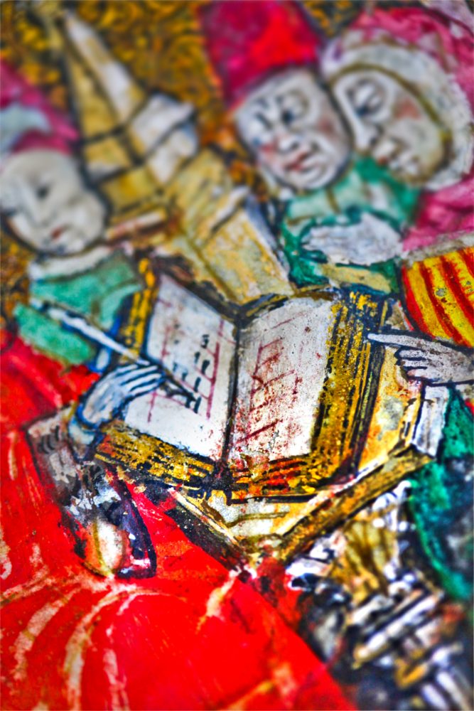 Medieval painting focused on an open book and the hand of a scribe.