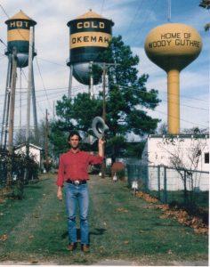 Larry Long stands by the water towers in Okemah, Oklahoma, the hometown of Woody Guthrie. Image courtesy of Long. (Photo/Jacqueline Long)
