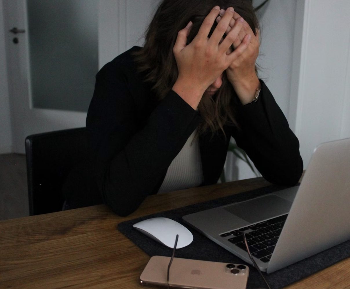 Frustrated person working at a laptop.