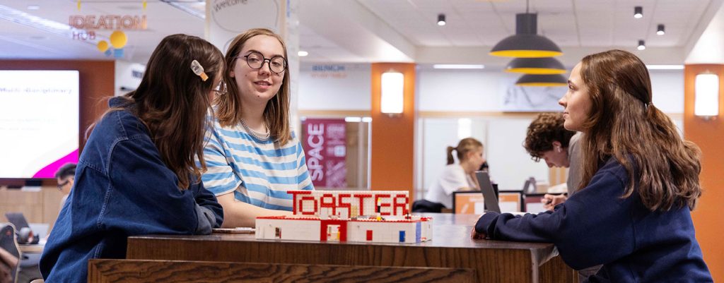 Three students gathered around a table in the Toaster Innovation Hub