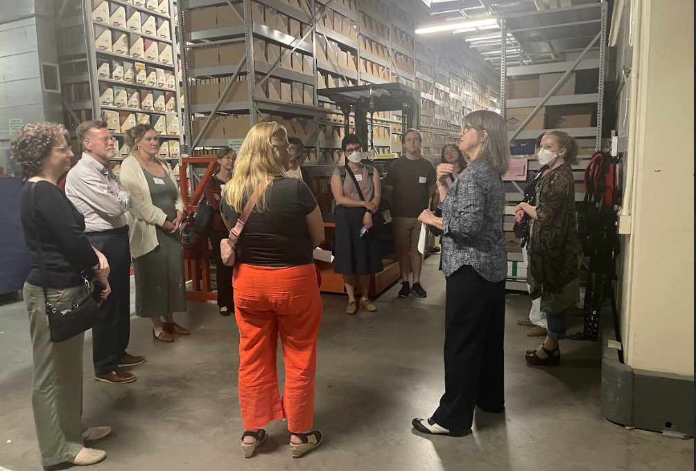 Guests gather in a circle around archivist Linnea Anderson in the caverns under Andersen Library