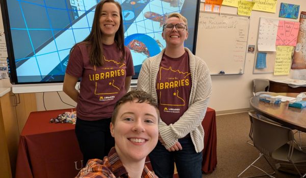 Three individuals in a classroom, posed in front of a screen showing virtual reality experiences.