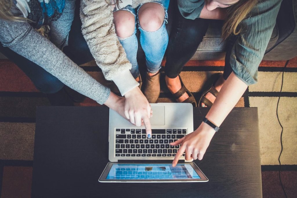 Three students clustered around open laptop