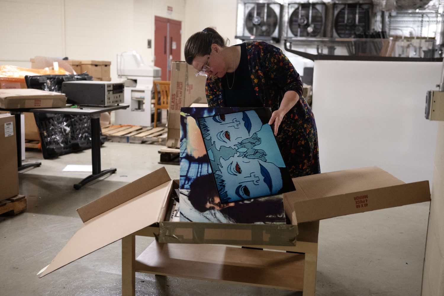 Woman pulls pictures from a cardboard box.