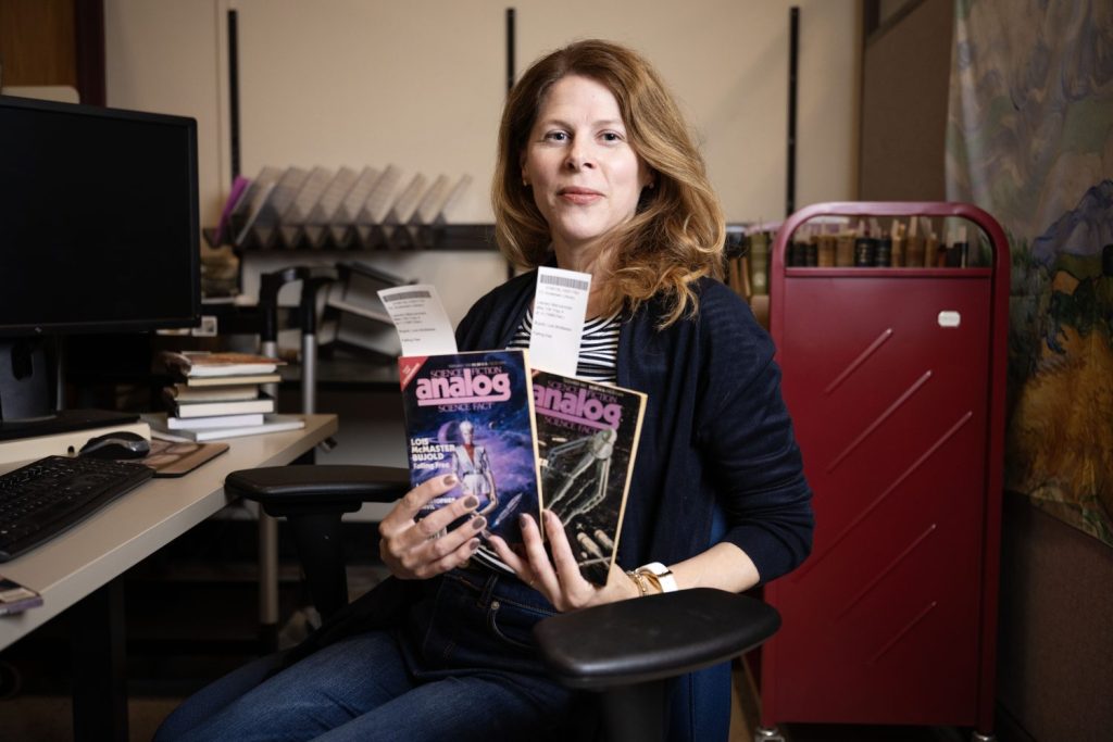 Woman fans out two copies of a science fiction magazine.